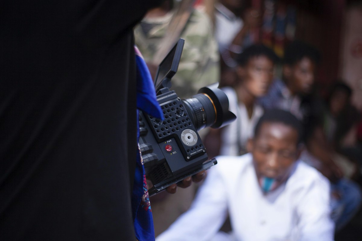 Filming an event with a professional camera, crowd behind